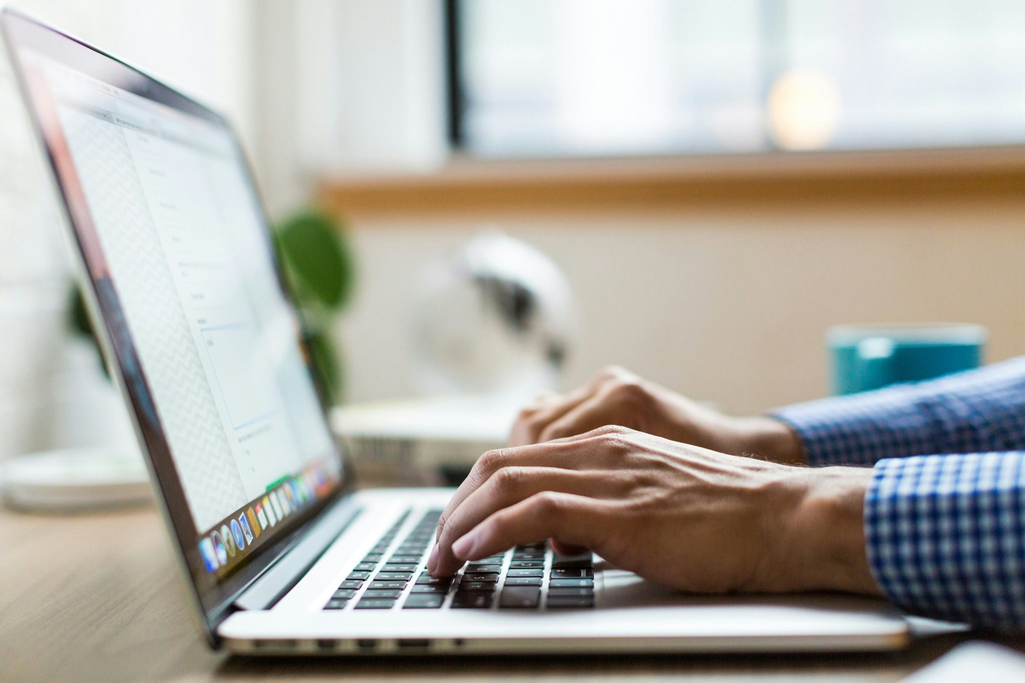 Man's hands typing on a laptop.